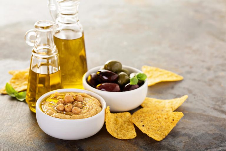 Olive oil homemade hummus with olives and crunchy corn chips. 