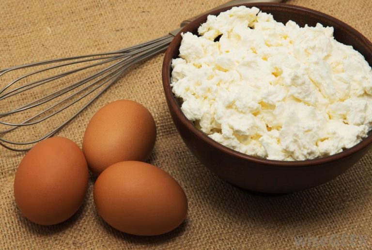 Three eggs whisk and bowl of cottage cheese